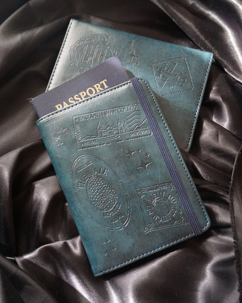 Two blue passport holders with embossed designs on a dark fabric background